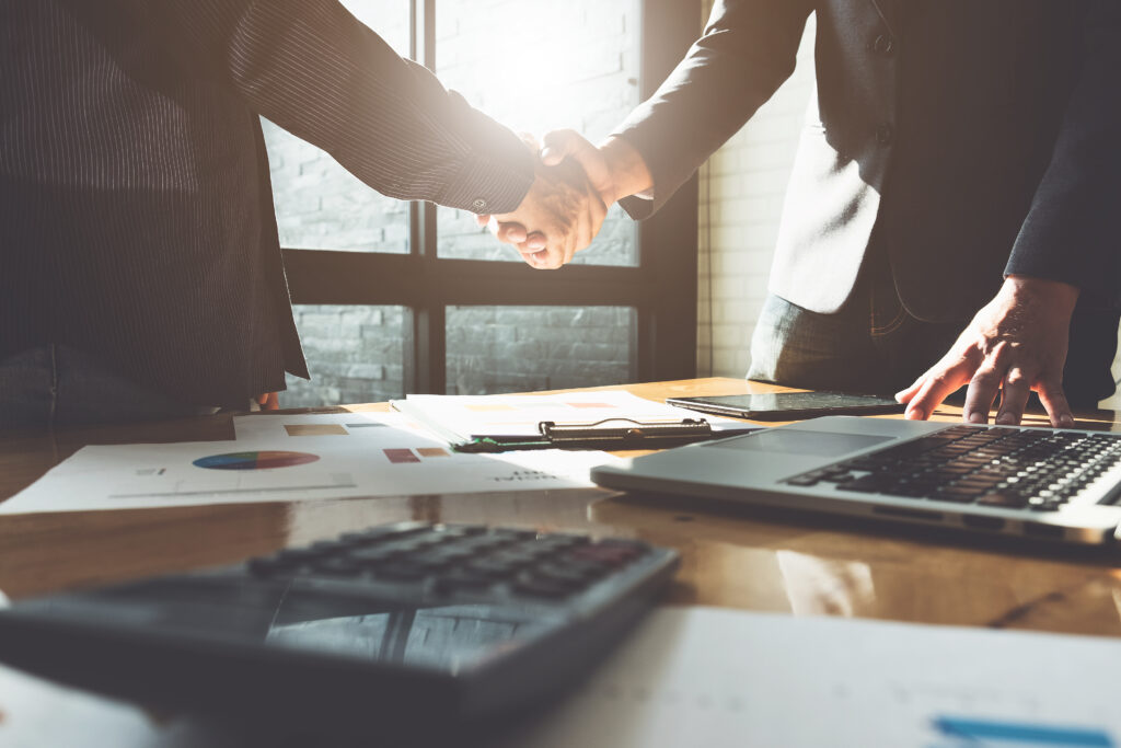 Adult site broker shaking client's hand above messy desk